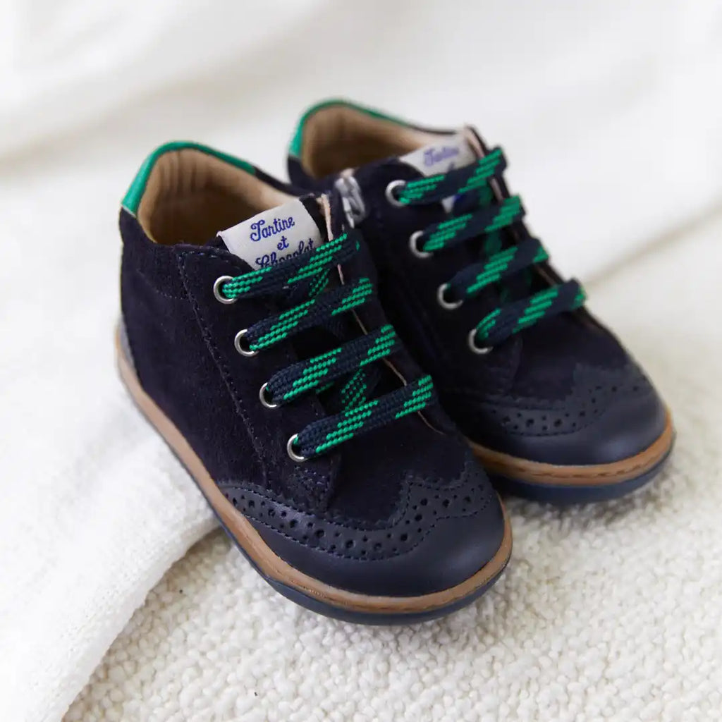 Bottes en suède bleu marine pour enfants avec des lacets verts et des détails en brogue.